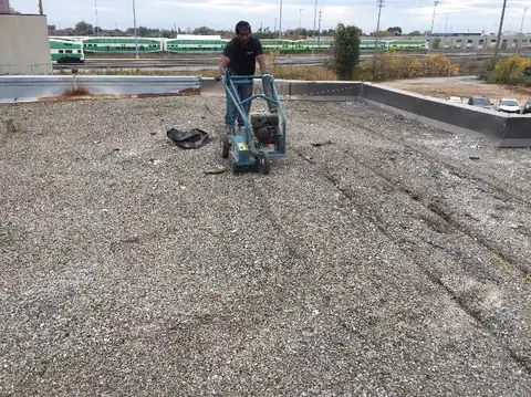 Old roof membrane is cut into strips for removal